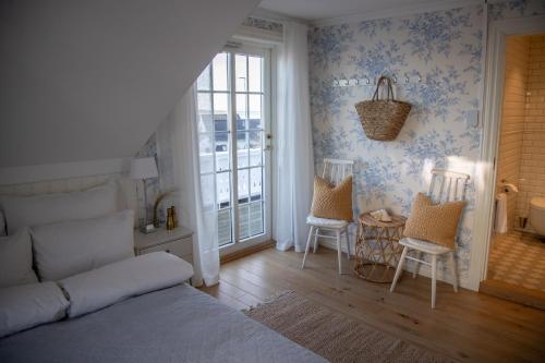 a bedroom with a bed and two chairs and a table at Nevlunghavn Gjestgiveri in Nevlunghavn
