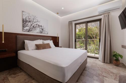 a bedroom with a large white bed and a window at Galatia Studios and Apartments in Benitses