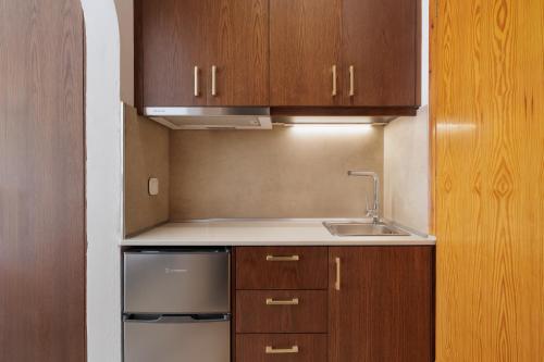 a small kitchen with wooden cabinets and a sink at Galatia Studios and Apartments in Benitses