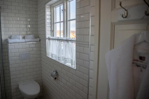 a white bathroom with a toilet and a window at Nevlunghavn Gjestgiveri in Nevlunghavn
