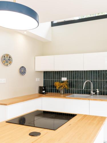 une cuisine avec des armoires blanches et un évier dans l'établissement Villa Canopy entre pins et plage, à Lit-et-Mixe