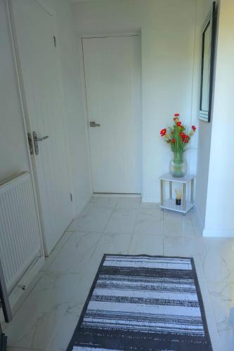 a hallway with a vase of flowers on a table and a door at Large House, Home for Contractors- Park Free in Chatham