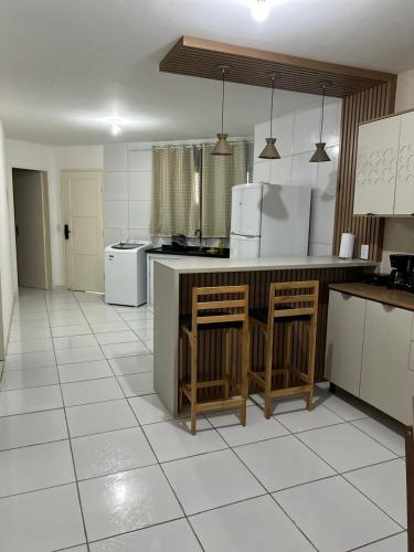 a kitchen with a counter and chairs in a room at Apto com Ar com vista para praia de Morro Branco - Fortaleza in Beberibe