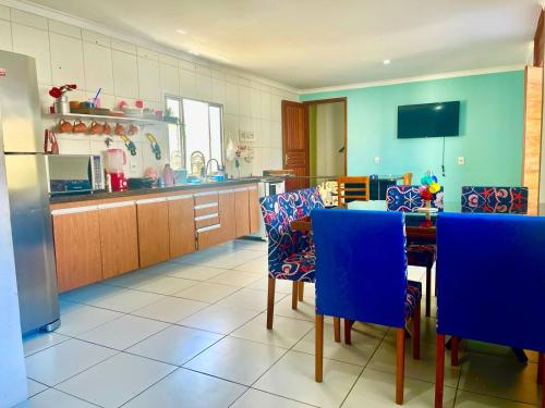 a kitchen with a table and some blue chairs at CASA de PRAIA ESPETACULAR CHURRAS, PISCINA E SINUCA in Jacaraípe