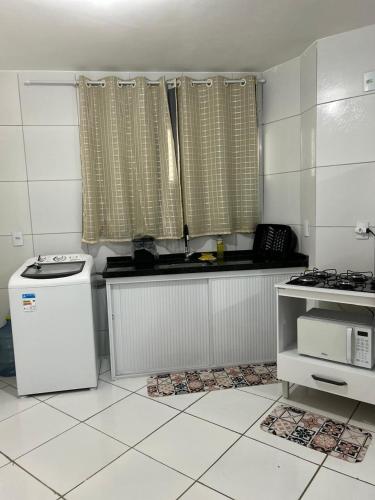 a kitchen with a sink and a stove and a microwave at Apto com Ar com vista para praia de Morro Branco - Fortaleza in Beberibe