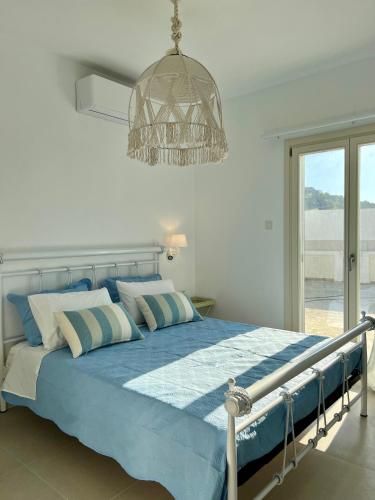 a bedroom with a blue bed with a chandelier at thEros - apartment 2 in Parikia