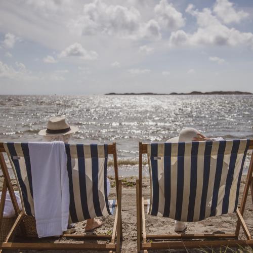 two people sitting on chairs on the beach at Nevlunghavn Gjestgiveri in Nevlunghavn