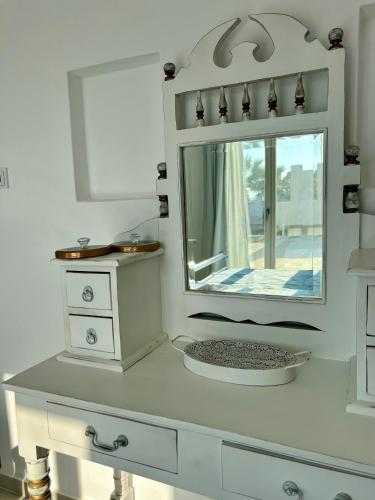 a white bathroom with a mirror and a sink at thEros - apartment 2 in Parikia