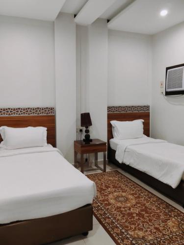 a bedroom with two beds and a table with a rug at منتجع شاطئ الدولفين للإيواء السياحي in Yanbu