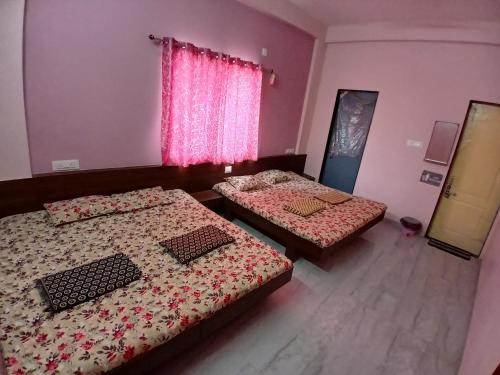 two beds in a room with pink walls at Krishna yatri Niwas in Akalkot