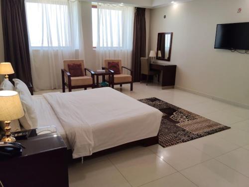 a hotel room with a bed and chairs and a television at منتجع شاطئ الدولفين للإيواء السياحي in Yanbu