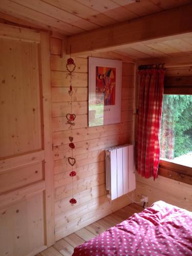 a log cabin bedroom with a bed and a window at Chalet Clarimaud in Bréchaumont
