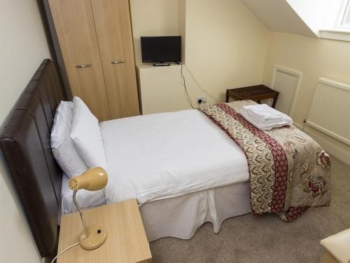 a bedroom with a bed and a table with a lamp at The Golf Hotel in Silloth
