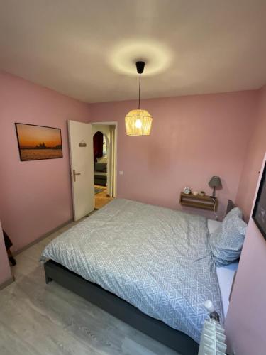 une chambre avec un lit et un mur rose dans l'établissement Maison avec petit jardin privatif tout confort, à Nandy