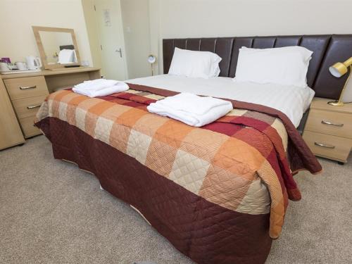 a bed with a blanket and two pillows on it at The Golf Hotel in Silloth