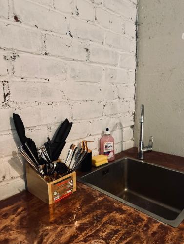a kitchen sink with utensils in a container next to a wall at Gypsy Camp Apartments & Glamping in Liepāja