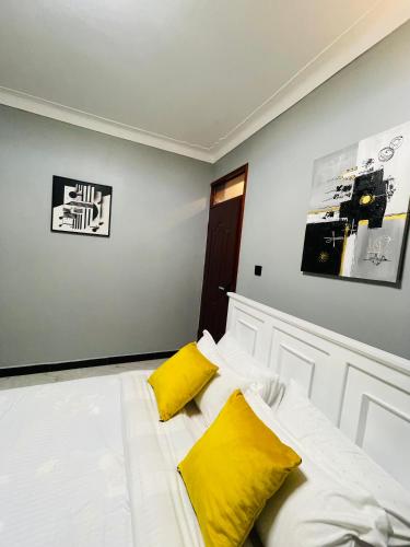 a bedroom with a white bed with yellow pillows at Enjoi Homes in Bulambiro