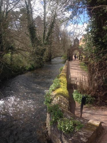 a river with people walking on a path next to it at Dunster Mill House in Dunster