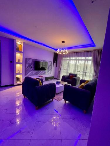 a living room with purple lighting and couches at Enjoi Homes in Bulambiro