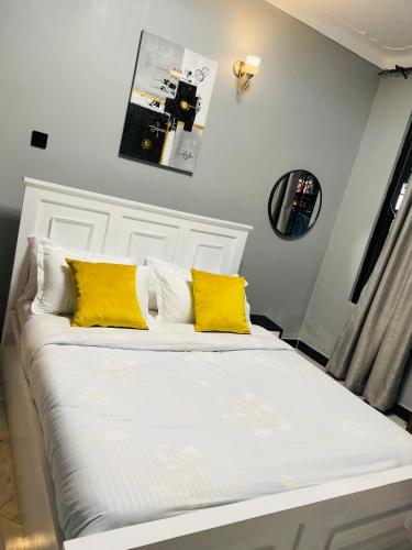 a white bed with two yellow pillows on it at Enjoi Homes in Bulambiro