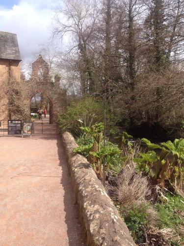 a stone wall next to a garden and a building at Dunster Mill House in Dunster