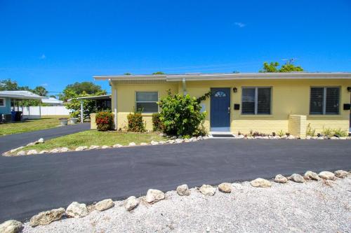 a yellow house with a blue door on a driveway at 2 BR Home With Private Beach Access To Golden Beach - Luna Sea in Venice