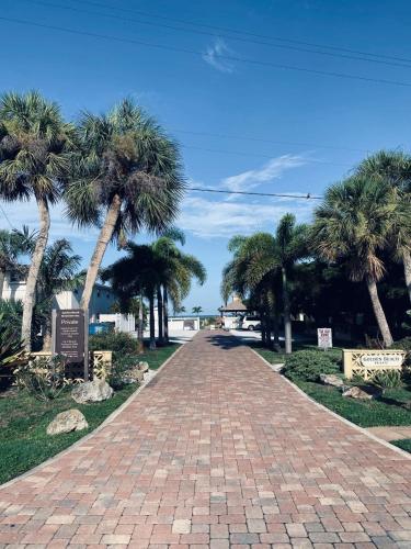 a brick road with palm trees on a beach at 2 BR Home With Private Beach Access To Golden Beach - Luna Sea in Venice