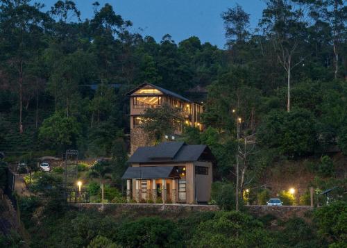 a house in the middle of a forest at night at Tea Terrain Resorts & Spa in Vagamon