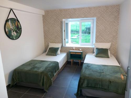 two beds in a room with a window at Spacieux T3 avec jardin dans belle béarnaise in Lanne-en-Barétous 