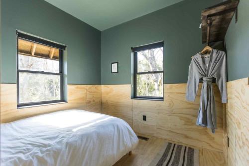 una camera da letto con un letto e due finestre di Lokal Chalet - Modern Cabin in the NJ Pine Barrens a Egg Harbor City