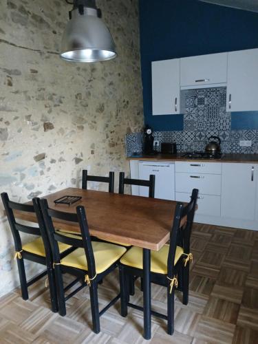 une cuisine avec une table et des chaises en bois dans l'établissement Le gîte des capucines, à LʼHerbergement