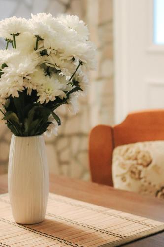 a white vase filled with white flowers on a table at Apartmani Matković in Žuljana