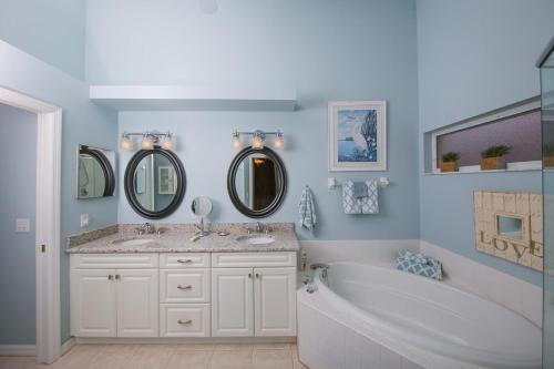 ein Badezimmer mit zwei Waschbecken und einer Badewanne und zwei Spiegeln in der Unterkunft Beautiful lakefront 2BR condo in Heritage Oaks Golf and Country Club in Vamo