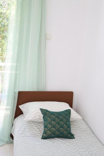 a bed with a green pillow and a window at Pampas Family Apartment in Dobrota