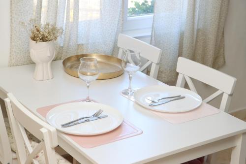 a white table with two plates and wine glasses at Pampas Family Apartment in Dobrota