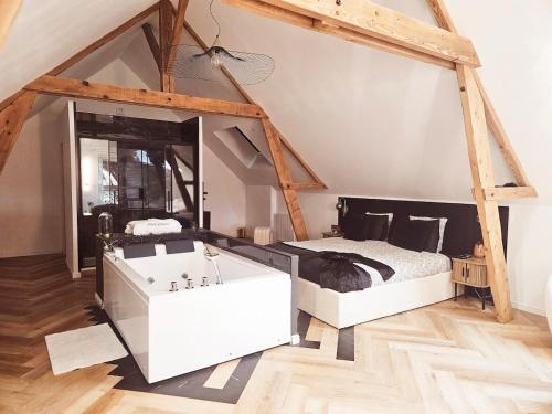 - une chambre avec un lit et une baignoire blanche dans l'établissement Black Romance, à Yville-sur-Seine