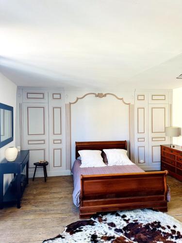 a bedroom with a wooden bed with white walls at Bel appartement Hôtel de ville in Bourganeuf