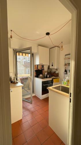 Il comprend une cuisine avec des placards blancs et du carrelage rouge. dans l'établissement Appartement ensoleillé et central à Marseille, à Marseille