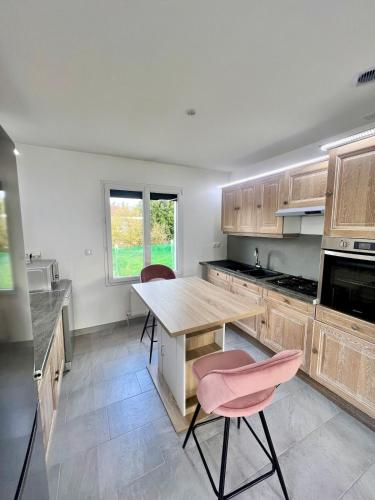 une cuisine avec une table en bois et deux chaises roses dans l'établissement Gîte des Passants, à Tourville-sur-Arques