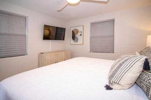 a bedroom with a white bed and two windows at Charming Manasota Key duplex with beach access- IB14 in Englewood
