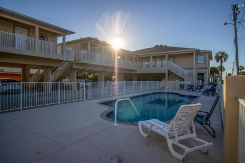 a swimming pool with two chairs and a building at Charming Manasota Key duplex with beach access- IB14 in Englewood