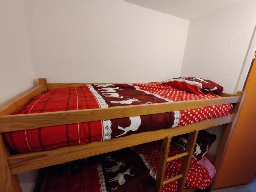 - une chambre avec 2 lits superposés et une couette rouge dans l'établissement Studio chaleureux à Barcelonnette avec balcon et vue montagne, à Barcelonnette