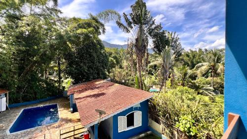 a blue house with a swimming pool and trees at Suites Oceano in Caraguatatuba