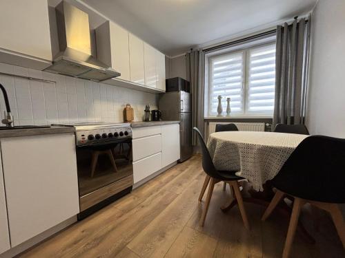 a kitchen with a table and a dining room at Apartamenty nad Zatoką in Jastarnia