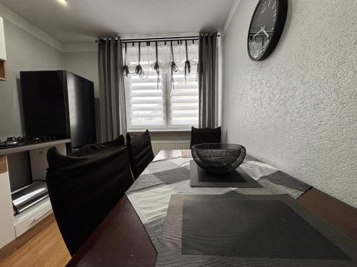 a dining room table with chairs and a clock on the wall at Apartamenty nad Zatoką in Jastarnia