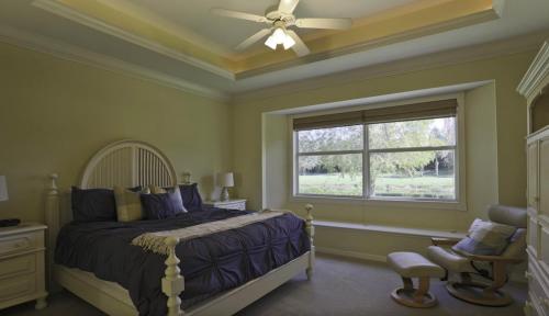 a bedroom with a bed with a ceiling fan and a window at Spacious 3BR home located in Tara Preserve with screened patio - Skippin Stones in Bradenton