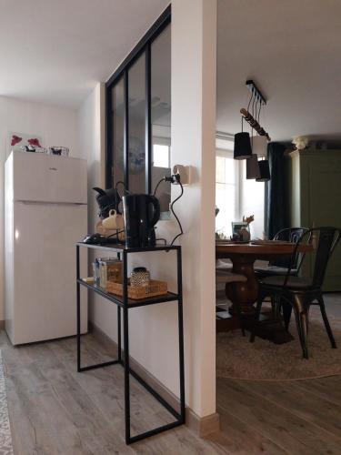 a living room with a table and a refrigerator at La Petite Bohème, sauna in Lorquin