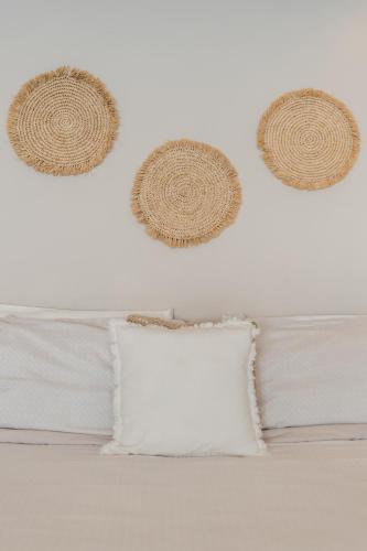 two straw hats are hanging above a bed with a pillow at *TURQUOISE ESCAPE- Beachfront Studio by Casa Paraiso* in Cancún
