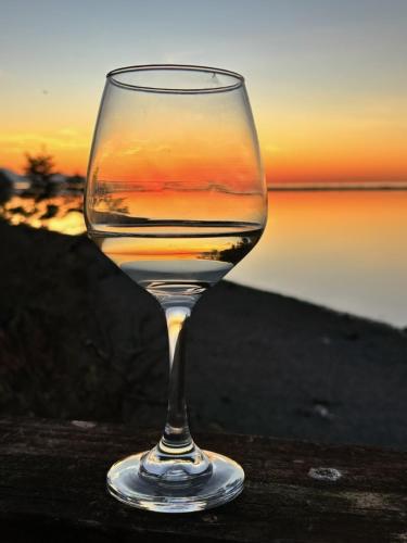 a glass of wine sitting on a table with the sunset at Dungeness Barn House Bed and Breakfast at Two Crows Farm in Sequim