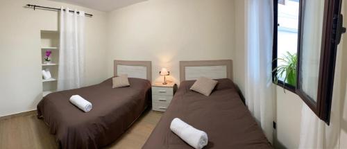two beds in a small room with a window at El Abuelo Manuel in Monachil